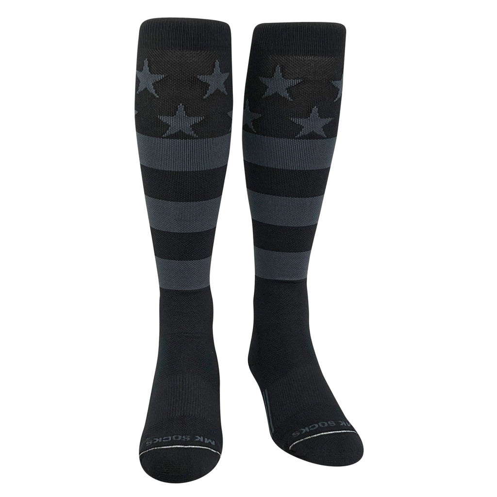 A pair of knee-high long sports socks with a USA flag design in black and graphite colors featuring stars and stripes.